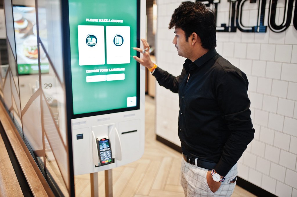 A man is ordering something using Self-Service Kiosks